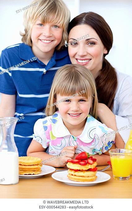 Portrait of a mother and her children having breakfast in the kitchen