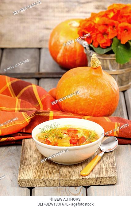Bowl of tomato and pepper soup on wooden table. Autumn setting