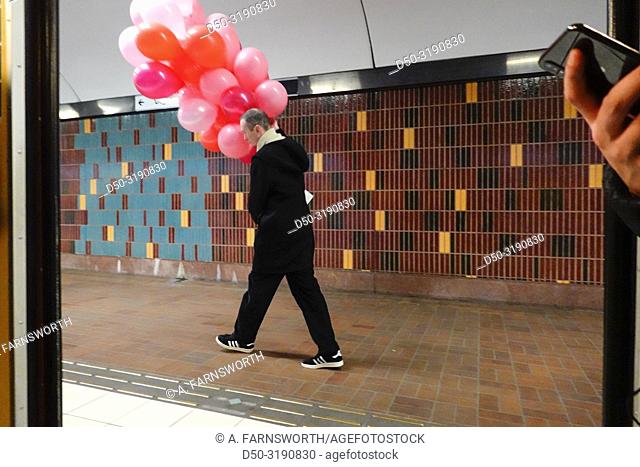 Stockholm, Sweden A man carries dozens of balloons onto the subway
