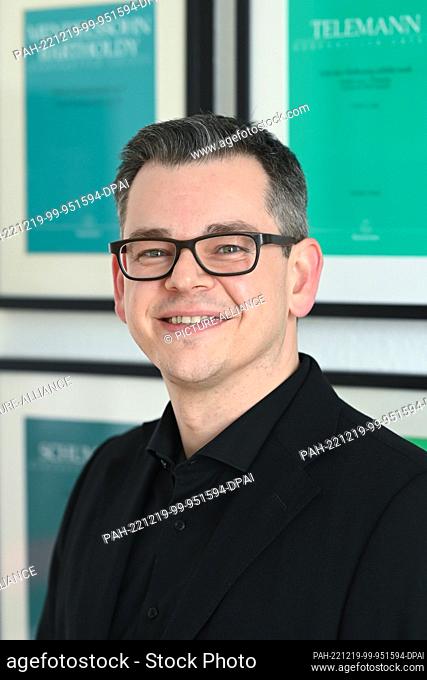 PRODUCTION - 16 December 2022, Hessen, Kassel: Clemens Scheuch, managing director of Bärenreiter Verlag, stands in front of the wall of title pages of Urtext...
