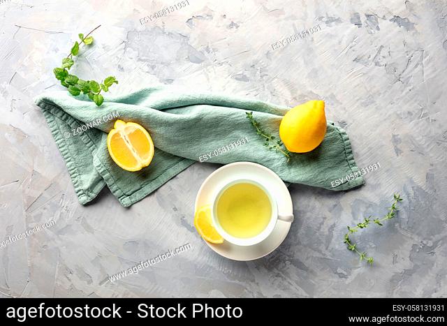 A cup of green tea with lemons and herbs, shot from the top with a place for text