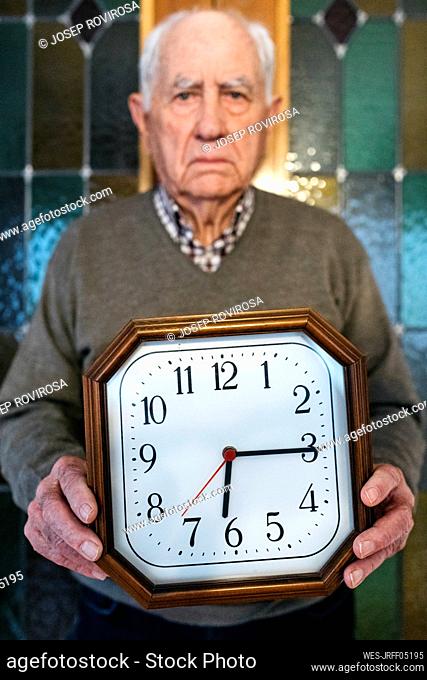 Man holding wall clock at home