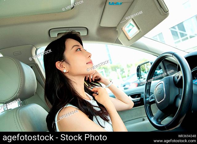 Young woman sitting in the car, look in the mirror