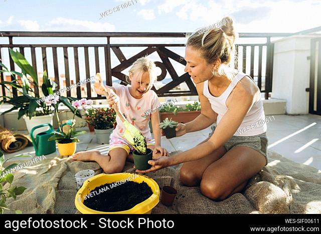 Mother and daughter planting on roof terrace together