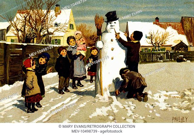 A group of children with a snowman in a field. Most of them are watching while two boys make the finishing touches, including a pipe in the snowman's mouth