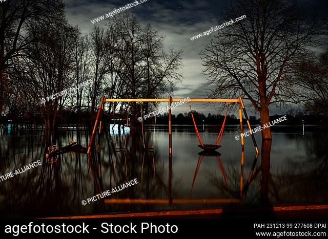 13 December 2023, North Rhine-Westphalia, Cologne: A swing frame in a playground stands in the flood waters of the Rhine