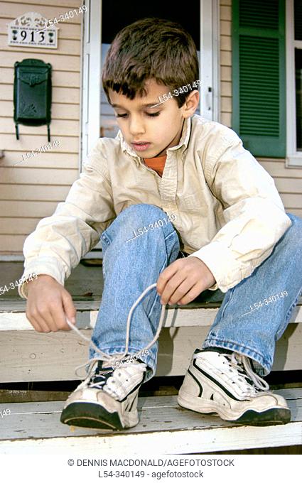 Four years old boy learning to tie shoes