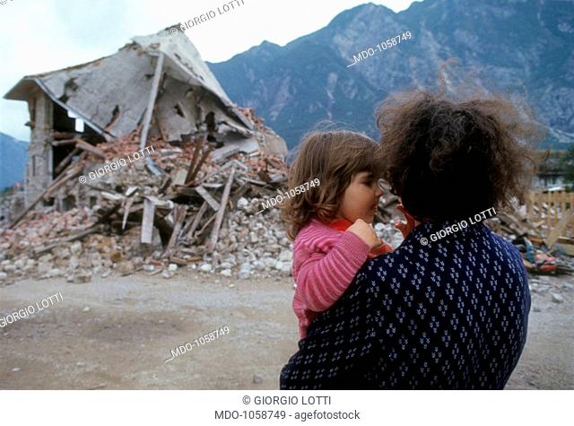 Friuli earthquake. A woman with a baby in her arms looks at the ruins of a house destroyed by the earthquake. Friuli-Venezia Giulia, May 1976