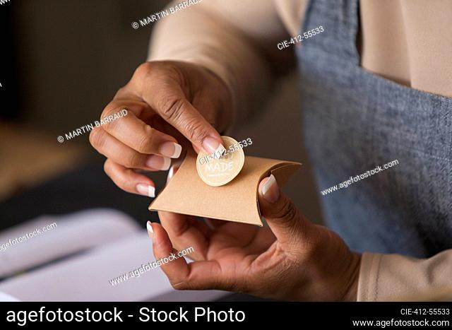 Close up female shop owner placing handmade label on box