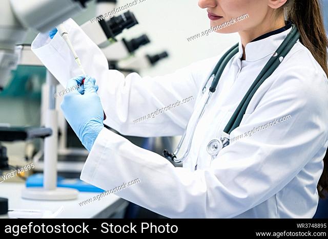 Doctor or lab assistant putting solution in blood test at the laboratory to be examined under the microscope