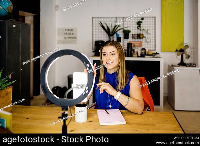 Happy businesswoman vlogging through smart phone in office