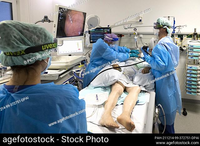 10 December 2021, Schleswig-Holstein, Kiel: Doctors and nurses care for a patient and adjust a feeding tube in one of the treatment rooms of the intensive care...
