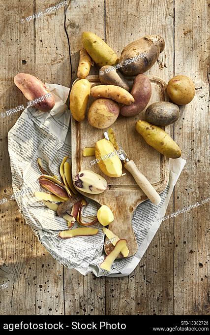 Colourful potatoes, partly peeled, on a wooden board
