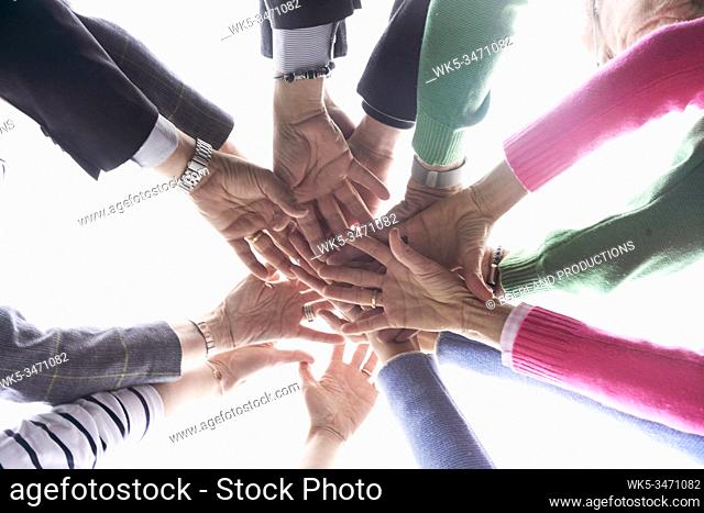 Group of friends putting hands together, directly below image