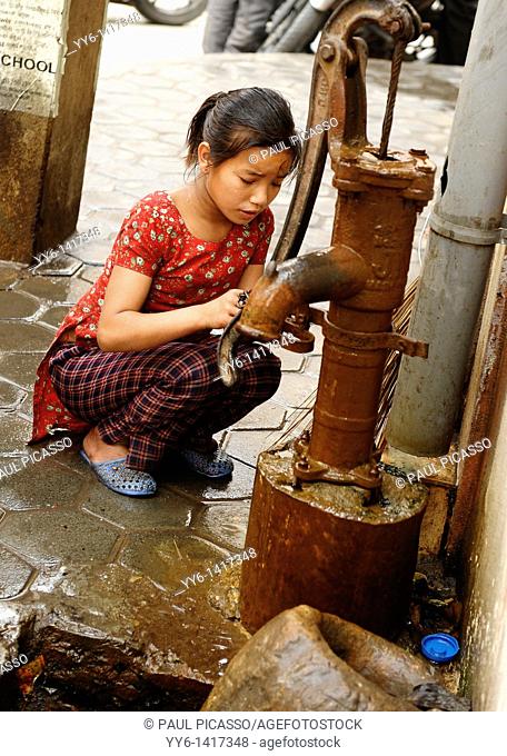 young girl collecting water from communal water pump, kathmandu street life , kathmandu, nepal