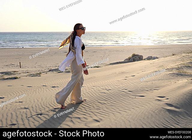 Young woman walking on sand dune at beach, Patara, Turkiye