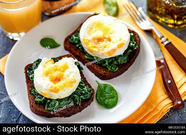 Two sandwiches with fried spinach and fried egg for Breakfast