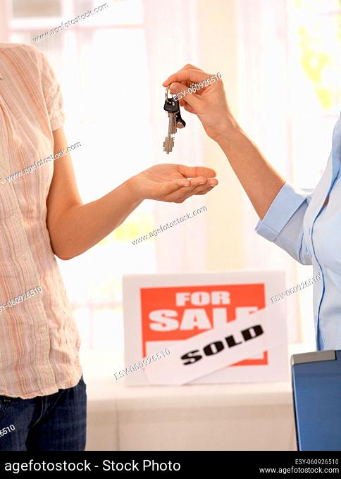Estate agent handing over keys of new house to young owner