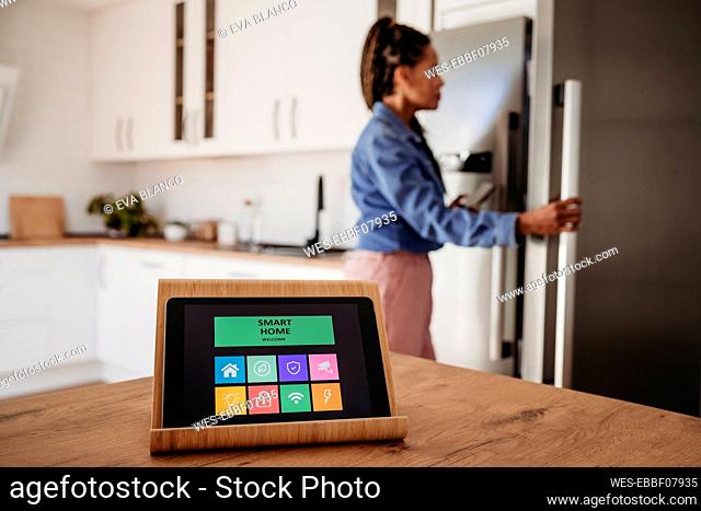 Home automation app on tablet computer with woman standing in background