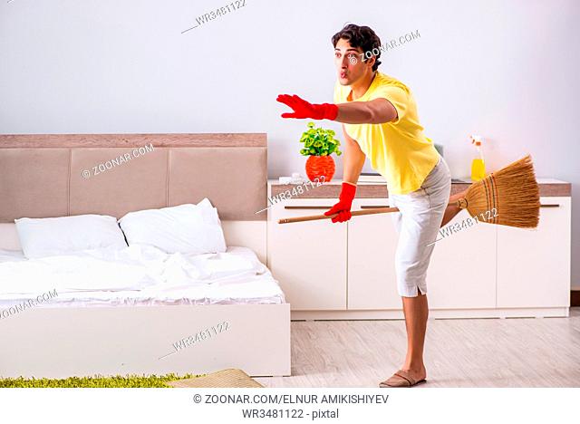 Young handsome man cleaning in the bedroom