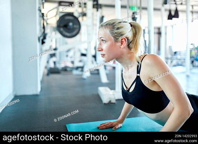 Junge Frau macht eine Pilates oder Yoga Übung auf der Matte im Gymnastik Kurs
