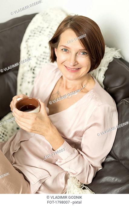 Portrait of mature woman smiling while sitting with hot drink