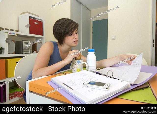 Young woman, student in her apartment, working while having breakfast