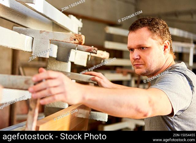 Junger Tischler als Möbelbauer beim Holz verleimen in der Tischlerei Werkstatt
