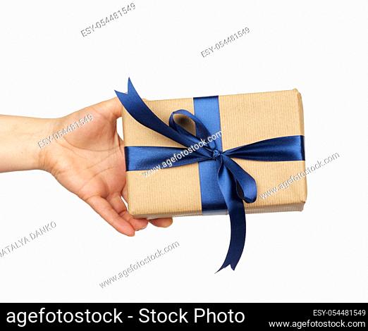 hand hold a wrapped gift in brown craft paper with tied silk blue bows, subject is isolated on a white background, concept of surprise and gift for the holiday