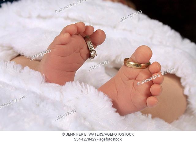 A newborn baby's feet, with the parents' wedding rings on his toes