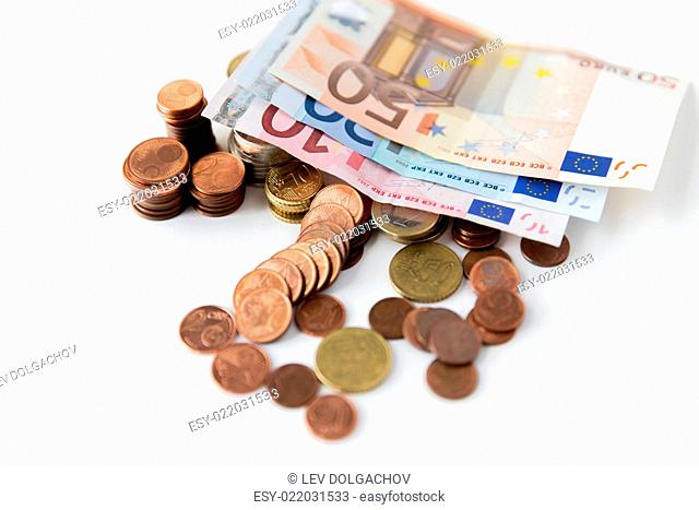 business, finance, investment, saving and cash concept - close up of euro paper money and coins on table