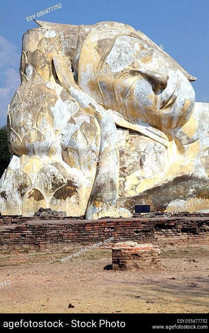 giant reclining buddha statue over blue sky at temple ruin