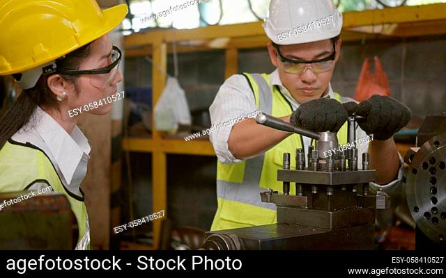 Asian professional mechanical engineer and operation team wearing uniform safety working metal lathe industrial manufacturing factory