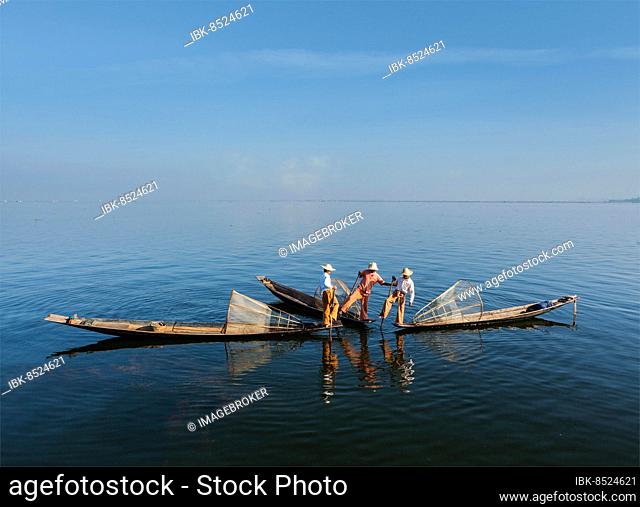 Myanmar travel attraction landmark, Traditional Burmese fishermen with fishing nets on boats at Inle lake in Myanmar famous for their distinctive one legged...