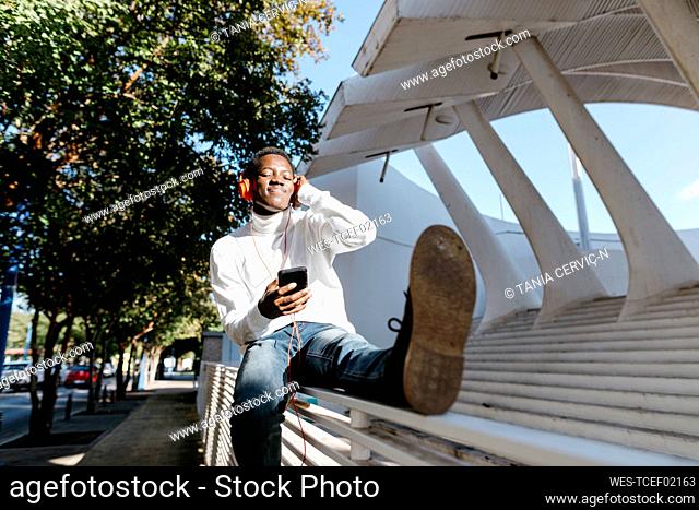 Man listening music with eyes closed on railing