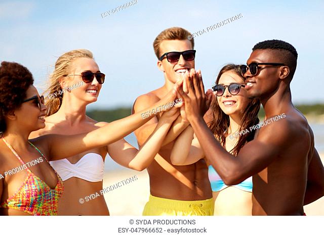 happy friends making high five on summer beach