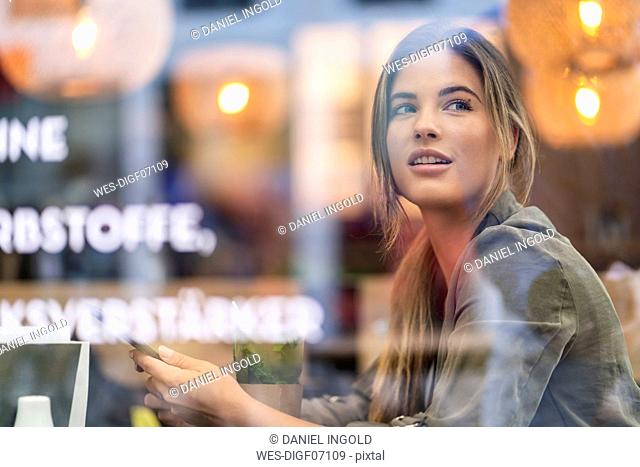 Young businesswoman in a cafe, seen through window