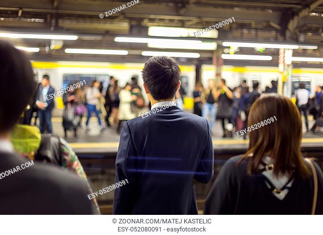 Passengers traveling by Tokyo metro. Business people commuting to work by public transport in rush hour. Shallow depth of field photo