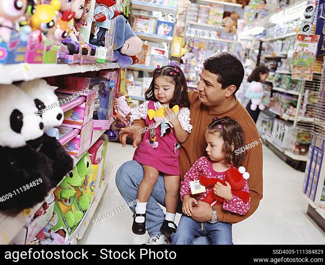 Hispanic father and young daughters at toy store