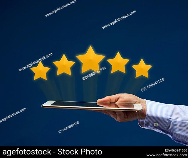 a female hand holds an electronic tablet and five yellow virtual stars above the screen. User rating of the application, service. Quality Rating