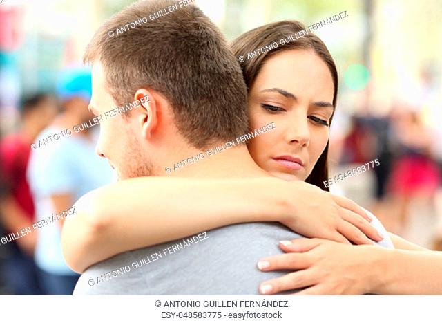 Discontent girlfriend hugging her partner on the street