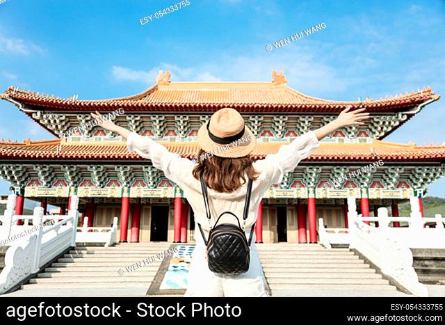 Young backpacker woman stand before traditional chinese temple