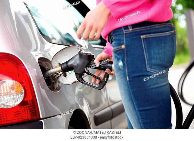 Lady pumping gasoline fuel in car at gas station