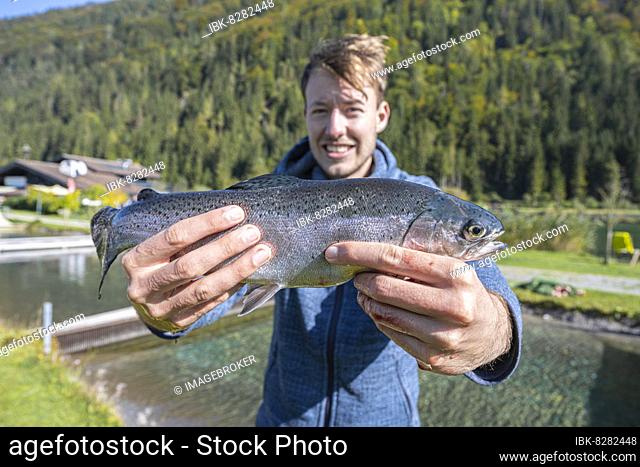 Man holding caught trout, fishing