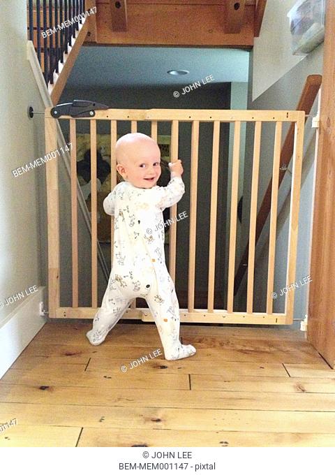 Caucasian baby standing at safety gate