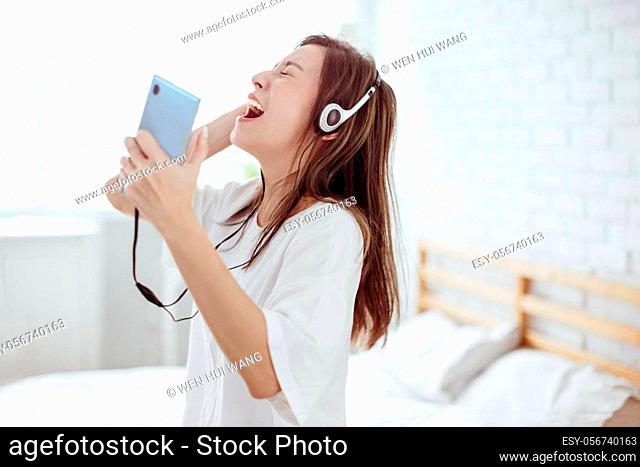 excited young woman holding mobile phone singing and yelling at home