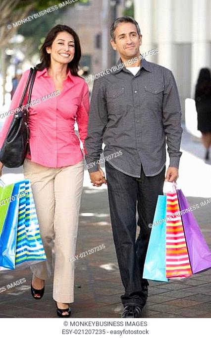 Couple Carrying Shopping Bags On City Street