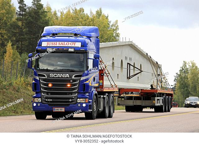 Blue Scania R560 semi trailer transports long precast concrete construction element in autumn in Orivesi, Finland - September 21, 2017