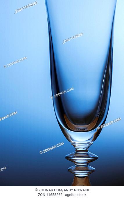 Oberer Teil eines geschwungenen Sektglases vor hellblauen Verlauf. Upper part of a sweeping champagne glass in front of light blue gradient