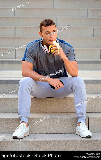 Young latin man eating banana fruit runner fitness portrait format sports training outdoor